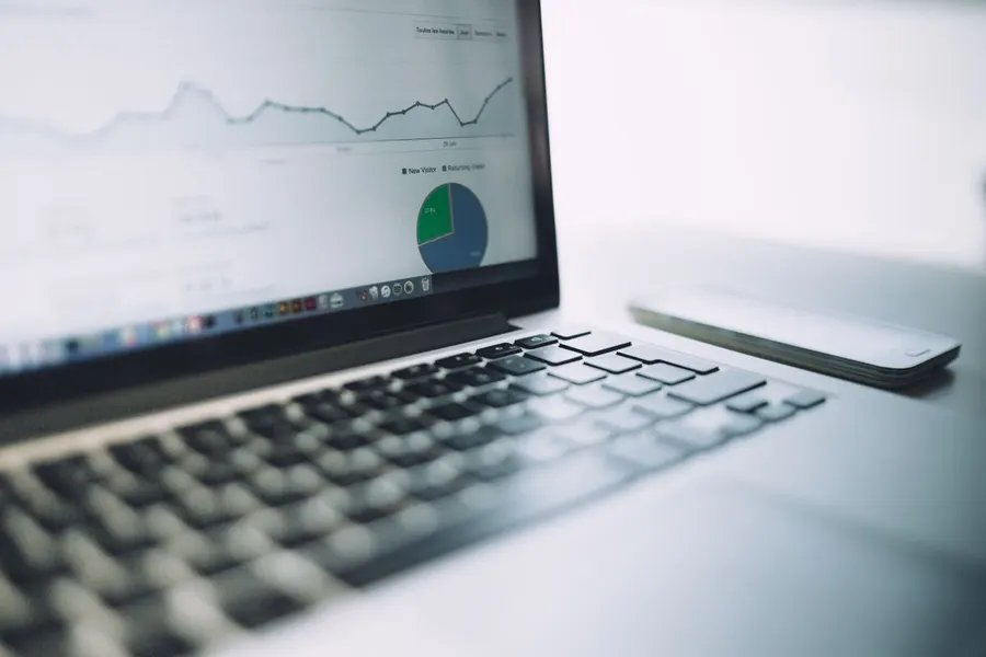 A smartphone and notebook with marketing analytics on a desk.