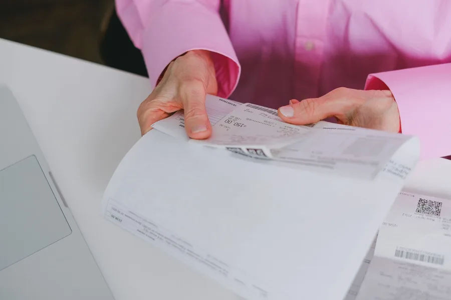 A person at a desk sorting supplier receipts and invoices.