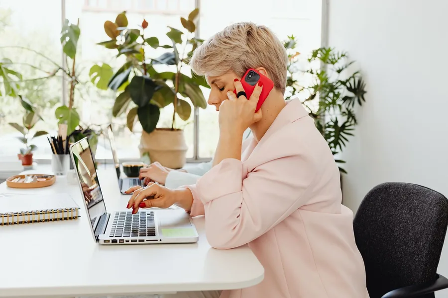 A finance manager on the phone at a desk with a laptop and paperwork.