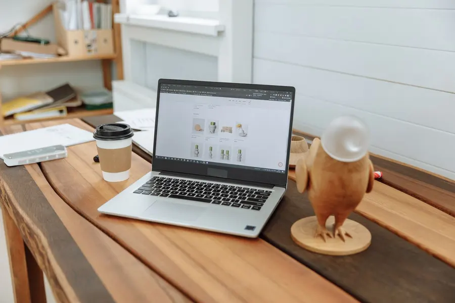 A laptop on a wooden desk showing a business website design in progress.
